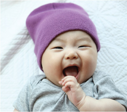 Baby laughing while looking at the camera.